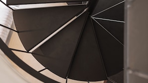 A spiral staircase with a modern design, featuring a central column and steps that ascend in a circular pattern. - Copal Simple Staying (Chania)