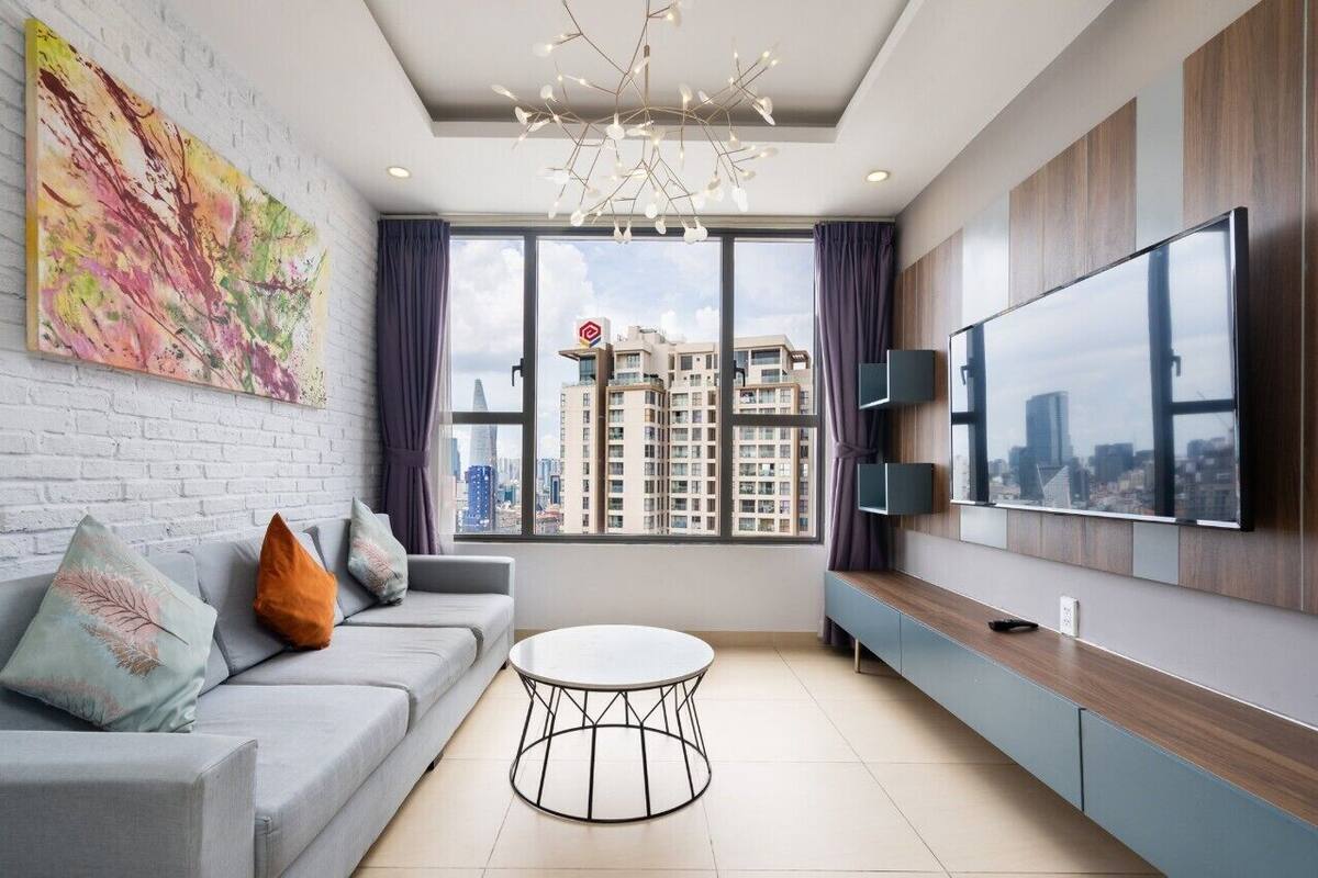 A modern living room with a grey sofa, a round coffee table, and a large TV on the wall.