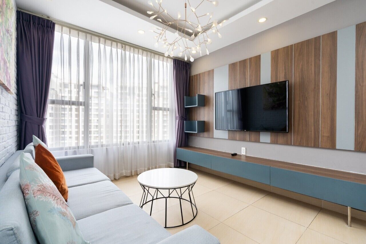 A modern living room with a sofa, a round coffee table, and a TV mounted on the wall.