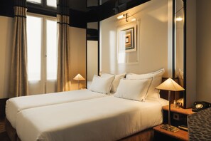 A hotel room with two beds, a nightstand with a lamp, a mirror, and a framed picture on the wall. - Hôtel du Château d'Eau - Touriste (Paris)