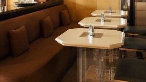 A modern hotel lobby with a brown sofa, clear glass tables, and a lamp.