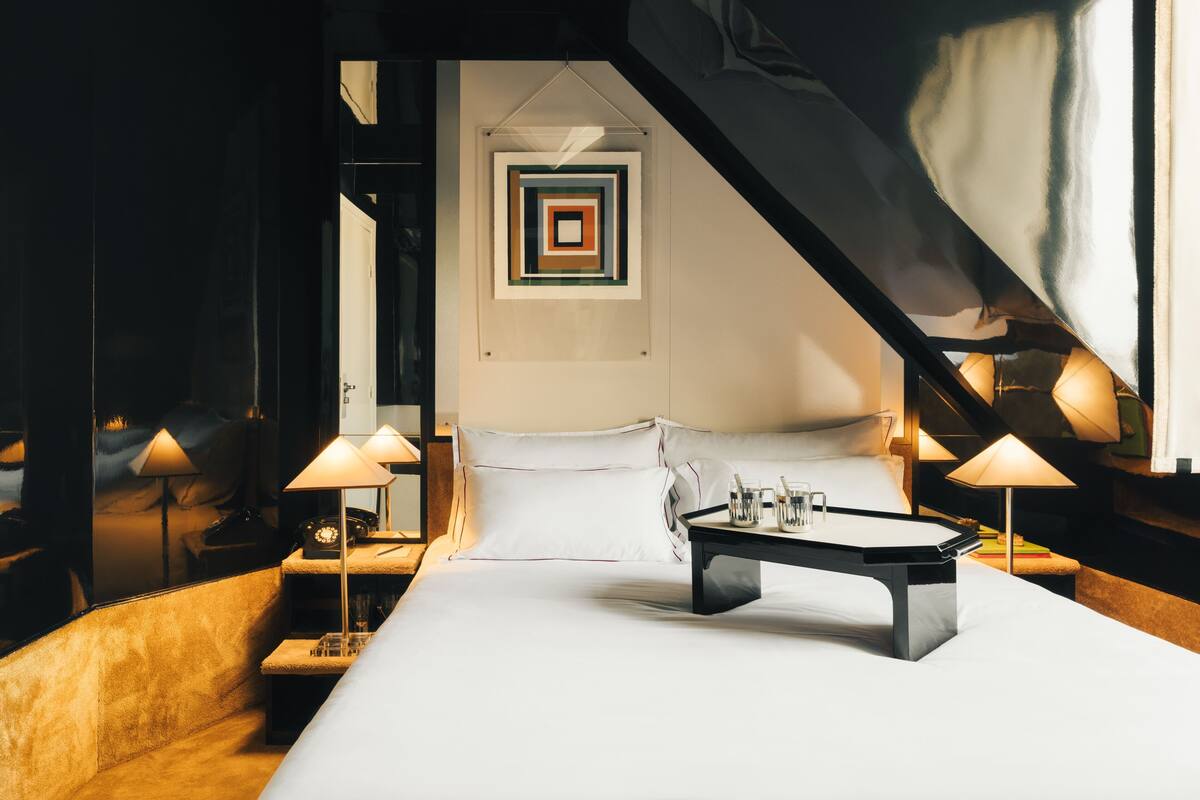A modern hotel room with a large bed, a desk, and two lamps.