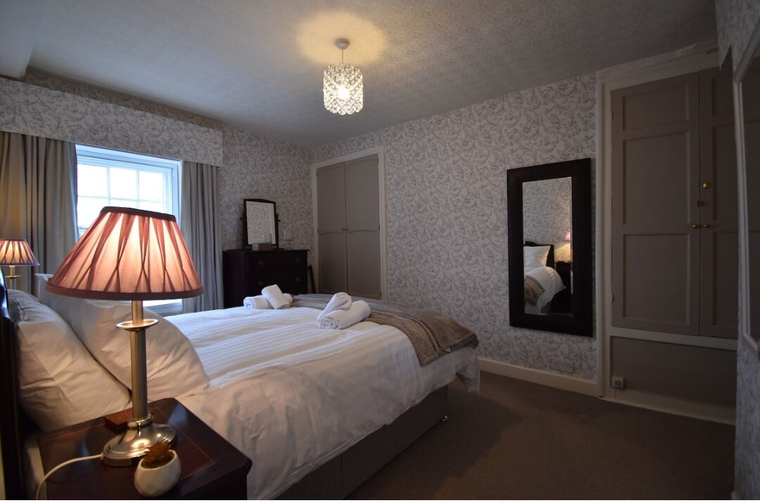 Ein Hotelzimmer mit einem großen Bett, zwei Nachttischlampen, einem Spiegel und einem Kleiderschrank.