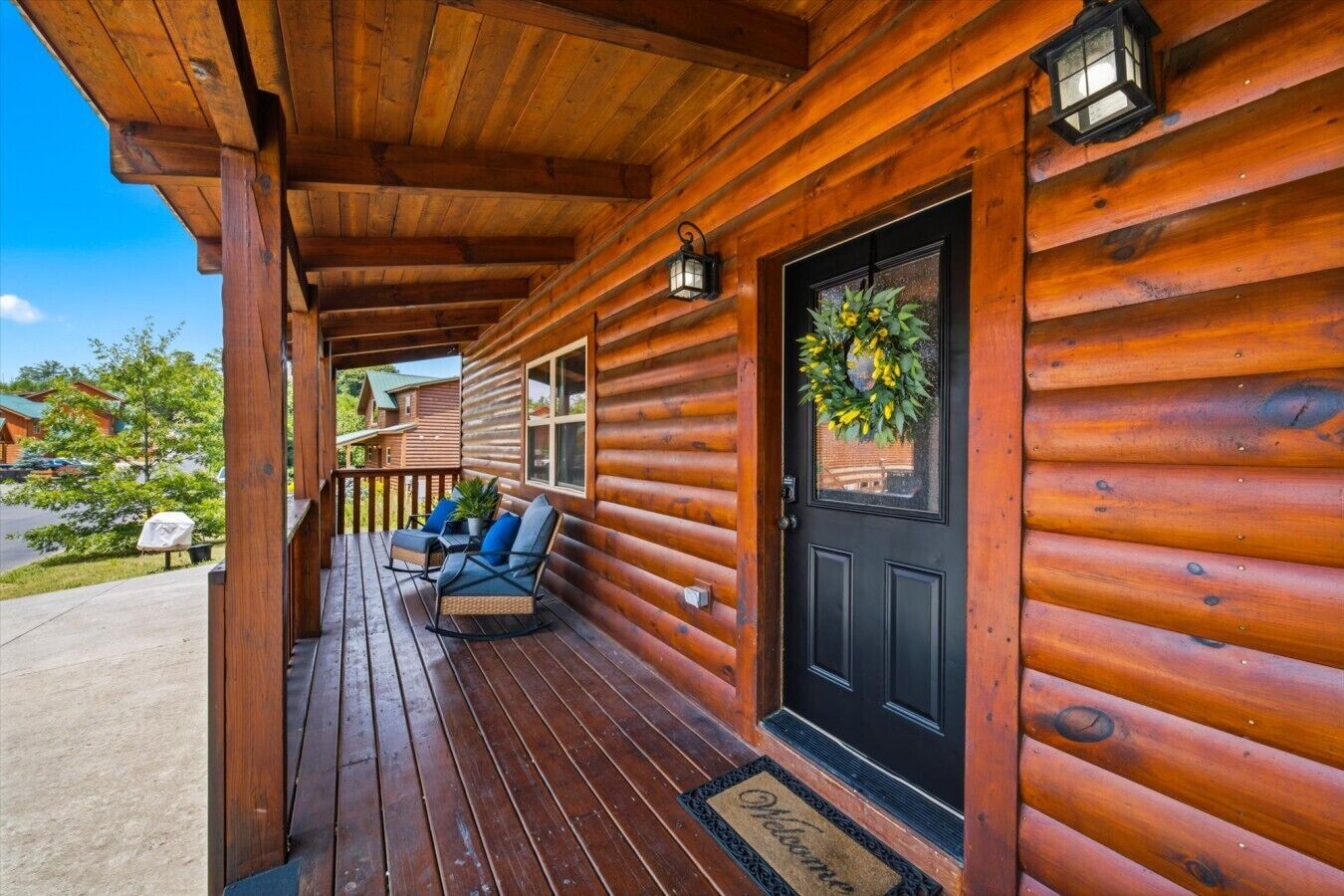 A wooden cabin with a porch, a black door, and a welcome mat.