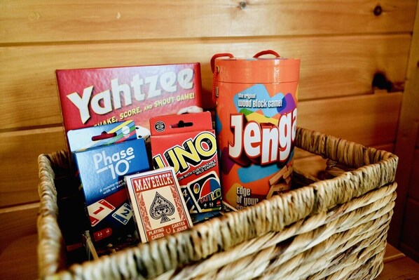 A basket containing various board games including Yahtzee, Jenga, and Uno. - Amazing Mountain View, Hot Tub, Game Room! (Sevierville)