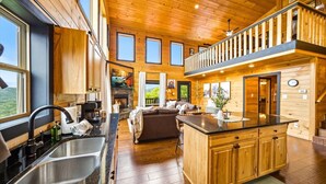 A spacious cabin with a large kitchen, dining area, and a cozy living room with a fireplace. - Amazing Mountain View, Hot Tub, Game Room! (Sevierville)