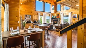 A wooden cabin interior with a dining area, kitchen, living room, and fireplace. - Amazing Mountain View, Hot Tub, Game Room! (Sevierville)
