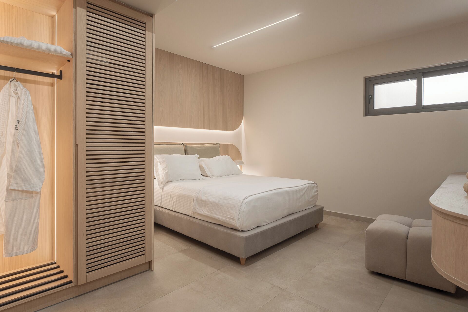 A modern bedroom with a bed, a wardrobe, and a vanity area.