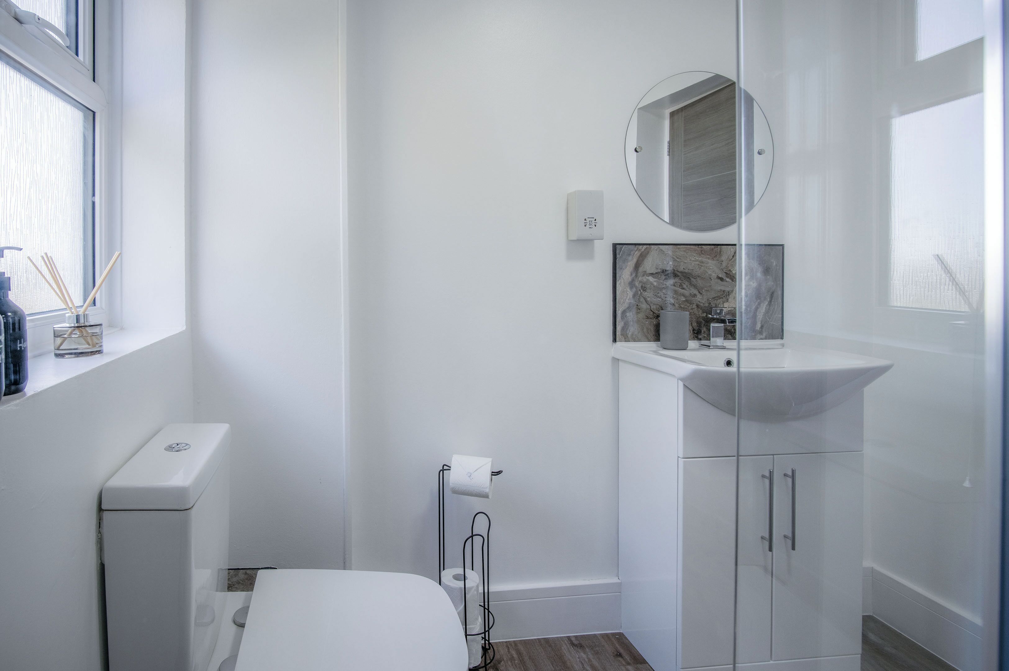 A modern bathroom with a toilet, sink, and mirror.