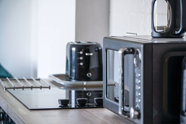 Une cuisine avec un grille-pain et un four à micro-ondes posés sur un plan de travail en bois.