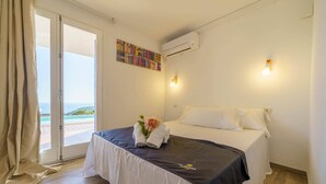Una habitación de hotel con cama, vista al mar y una estantería llena de libros.