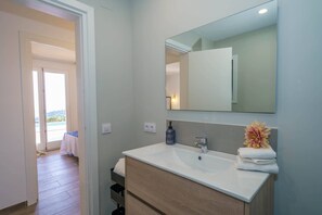 Une salle de bain moderne avec un grand miroir, un lavabo blanc et un meuble-lavabo en bois.