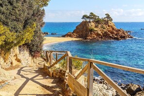 A coastal path leading to a beach with clear blue waters and rocky outcrops. - Villa Sea Breeze | Private Pool Panoramic Sea Views AC Ideal Families Tossa (Tossa de Mar)