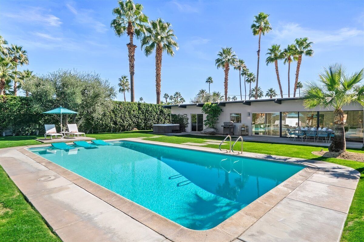 A rectangular swimming pool with a clear blue water surface, surrounded by a paved deck.
