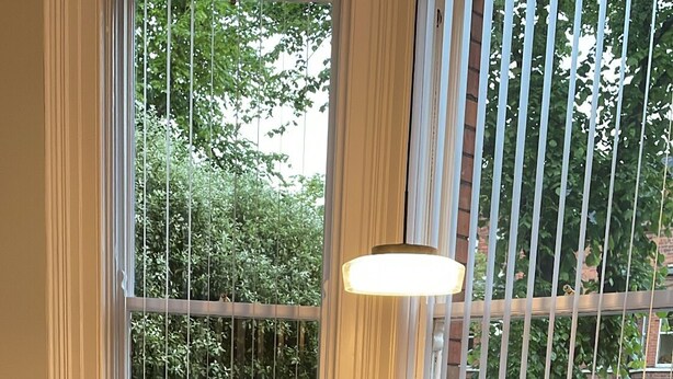 A dining area with a round glass table set for four, surrounded by white chairs with wooden legs. - CityGo Apartments Queens (Belfast)