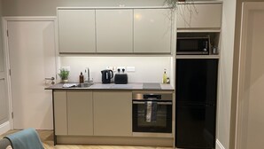 A modern kitchen with a built-in microwave, toaster, and dishwasher. - CityGo Apartments Queens (Belfast)