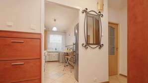 Une cuisine avec des meubles de rangement en bois, un miroir et un coin repas comprenant une table et des chaises.