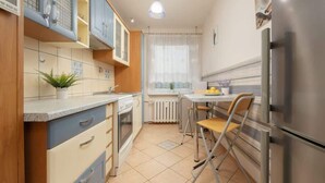 Une cuisine compacte équipée d’un réfrigérateur, d’un évier et d’un coin repas avec une table et des chaises.