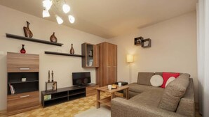 Un salon moderne avec un canapé, un téléviseur, un meuble en bois et des objets décoratifs disposés sur des étagères.