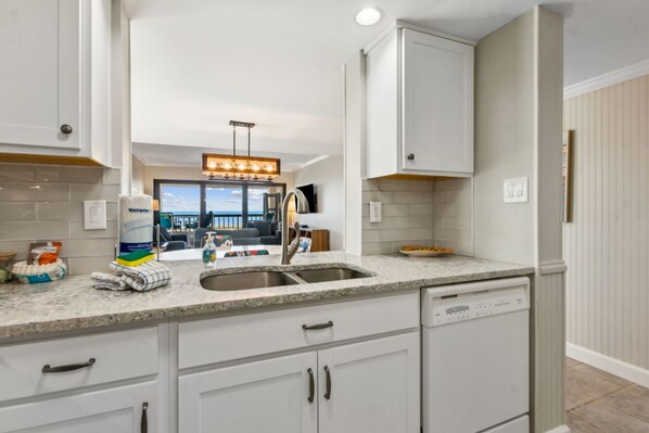 A modern kitchen with white cabinets, a granite countertop, and a built-in dishwasher.