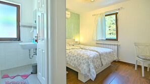 A bedroom with a bed, a window with curtains, a bedside lamp, and a chair. - Villa Gloria Vita by Villas Guide (Brtonigla)