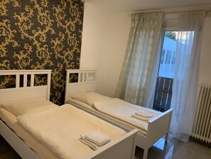 Ein Doppelzimmer mit zwei Einzelbetten, einem Fenster mit Blick und einer Wand mit Muster.