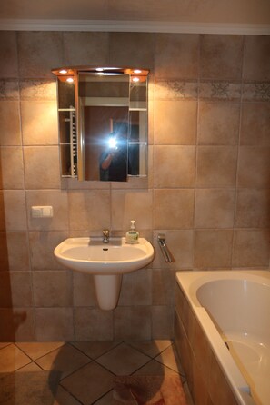 Ein Badezimmer mit Waschbecken, Spiegel und Badewanne.