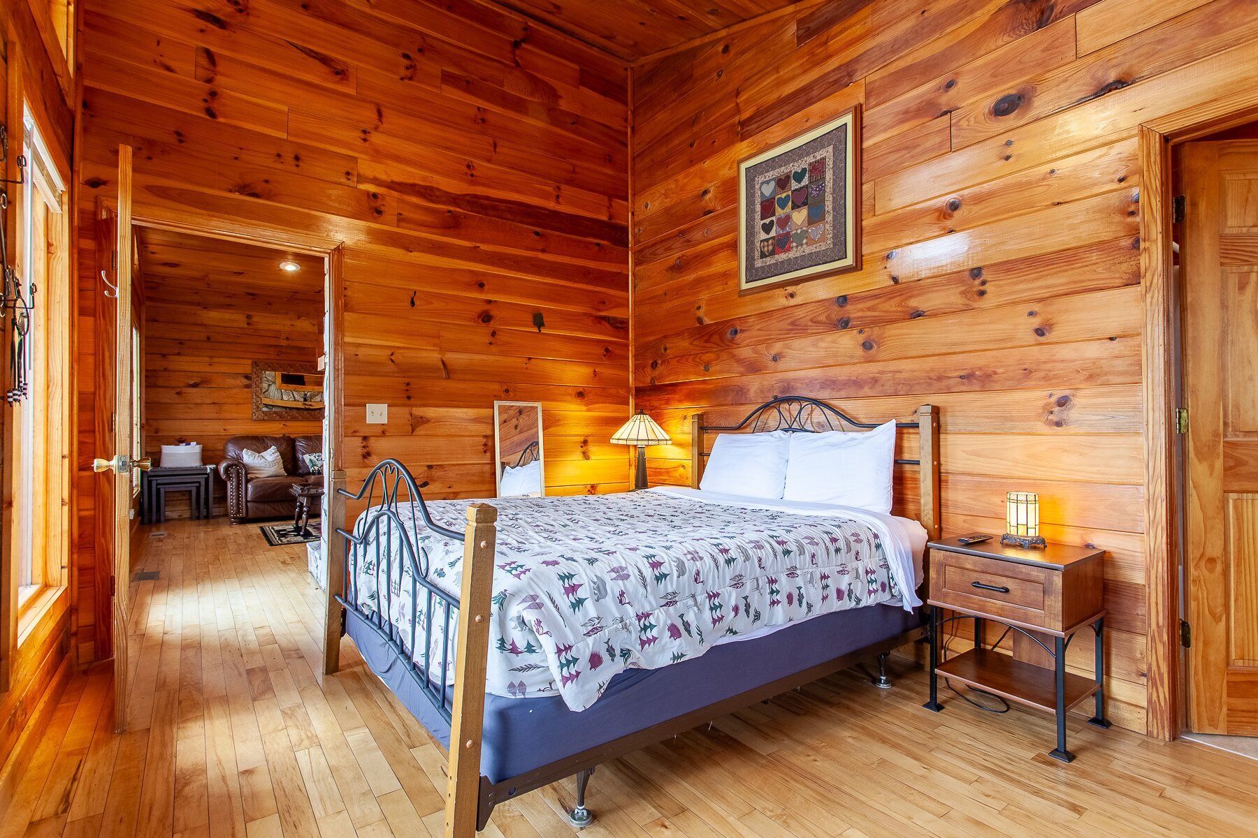 A wooden cabin bedroom with a bed, bedside tables, and a lamp.