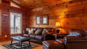 L’intérieur d’un chalet confortable, avec un canapé en cuir, une table basse en bois et une lampe.