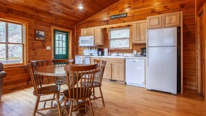 Une cuisine aménagée dans un style rustique, avec des murs en bois, une table à manger avec des chaises, un réfrigérateur et un four à micro-ondes.
