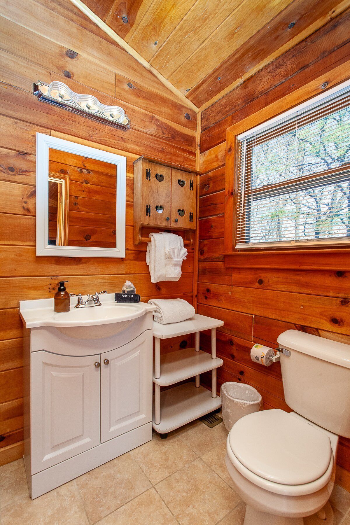 A wooden cabin bathroom with a white vanity, sink, and toilet.