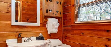 A wooden cabin bathroom with a white vanity, sink, and toilet.