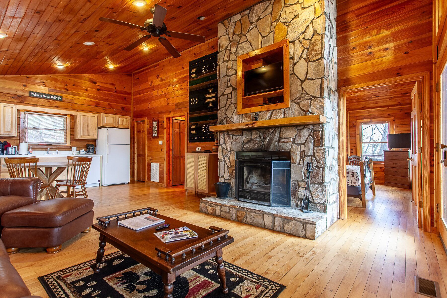 L’intérieur d’une cabane comprend une cheminée en pierre, un plafond en bois et un coin repas.