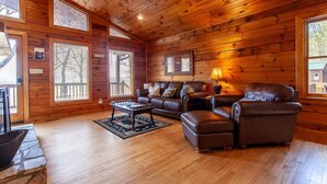 L’intérieur chaleureux d’un chalet avec des murs en bois, un canapé en cuir, une table basse et une cheminée.