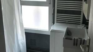 A small, bright bathroom with a window, a towel rack, and a sink.