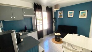 A compact kitchen with grey cabinets, a black countertop, and a white dining table.