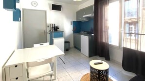 A compact kitchen with a dining area, a small table, and a window with curtains.