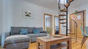Un soggiorno moderno con un divano grigio, un tavolino in legno e una poltrona blu.