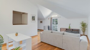 Un soggiorno moderno con un divano bianco, un piccolo tavolino e un pavimento in legno.