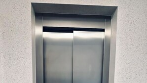 Ein moderner Aufzug mit Metalloptik und einer Bedienkonsole auf der linken Seite.