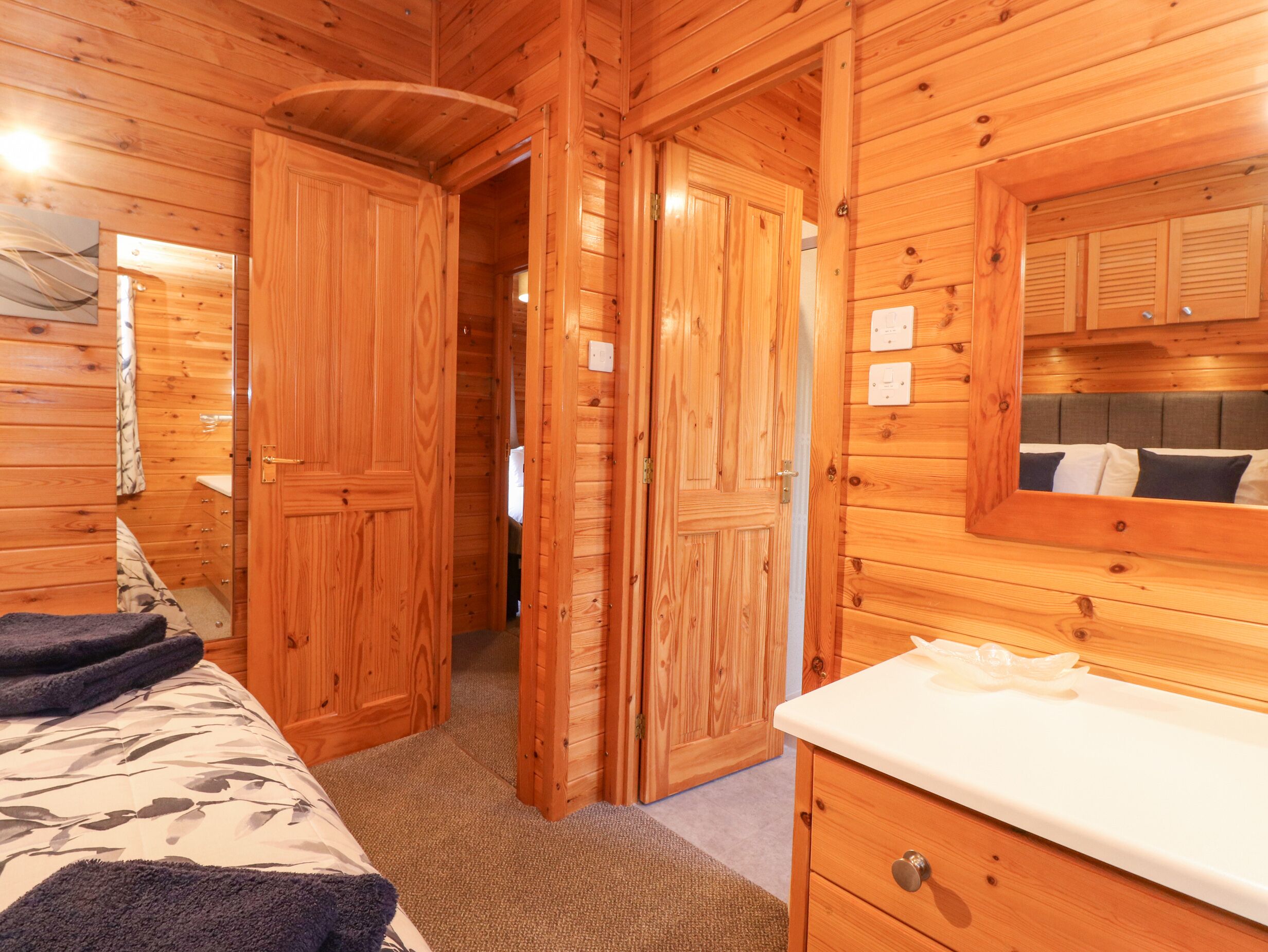 Een houten kamer met een bed, een kaptafel en een spiegel.