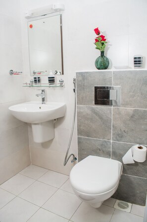 Un baño con lavamanos blanco, inodoro y ducha.
