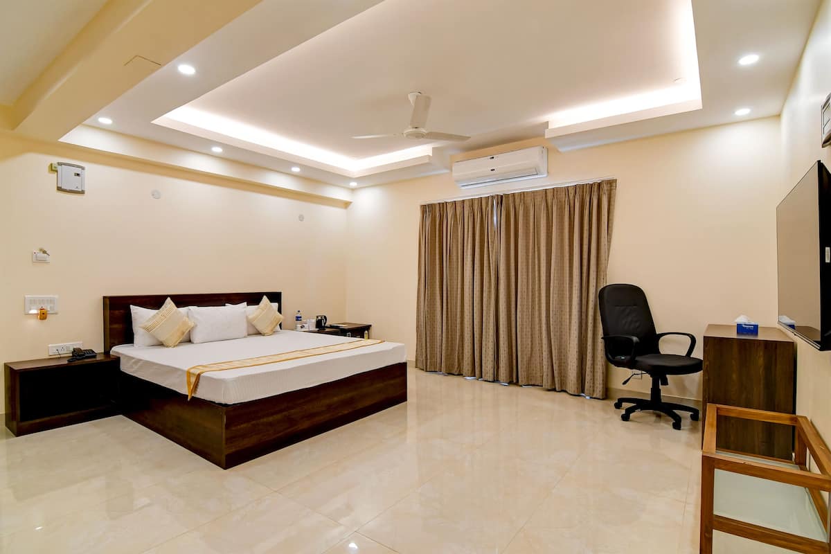 Una habitación de hotel con cama, mesita de noche, silla, escritorio y televisión.