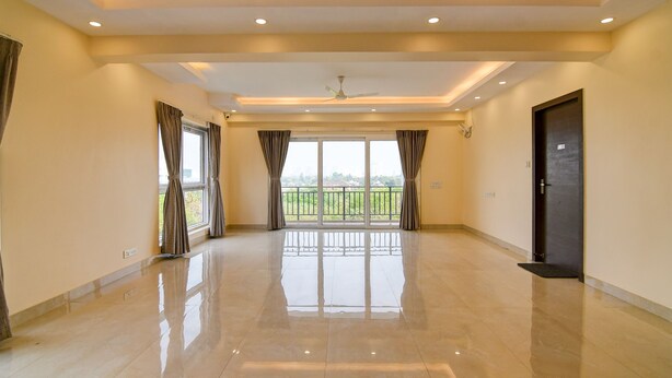 A spacious room with a balcony, large windows, and a polished floor. - AVS PRIME (Barasat)