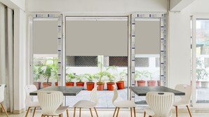 A modern dining area with a dark table and white chairs, potted plants, and a view of the outside. - AVS PRIME (Barasat)