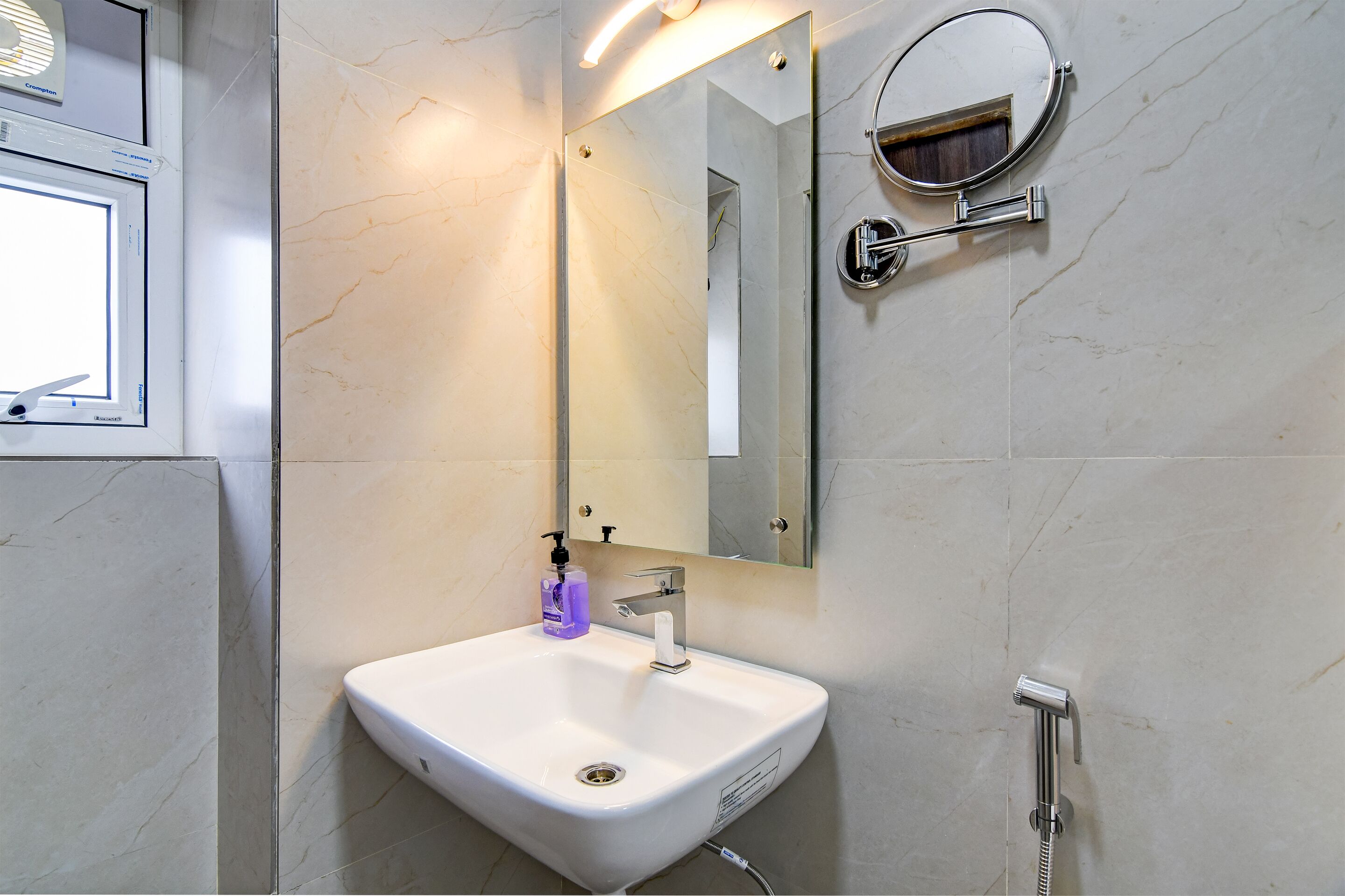 Een badkamer met een wit wastafel, een spiegel en een handdouche.