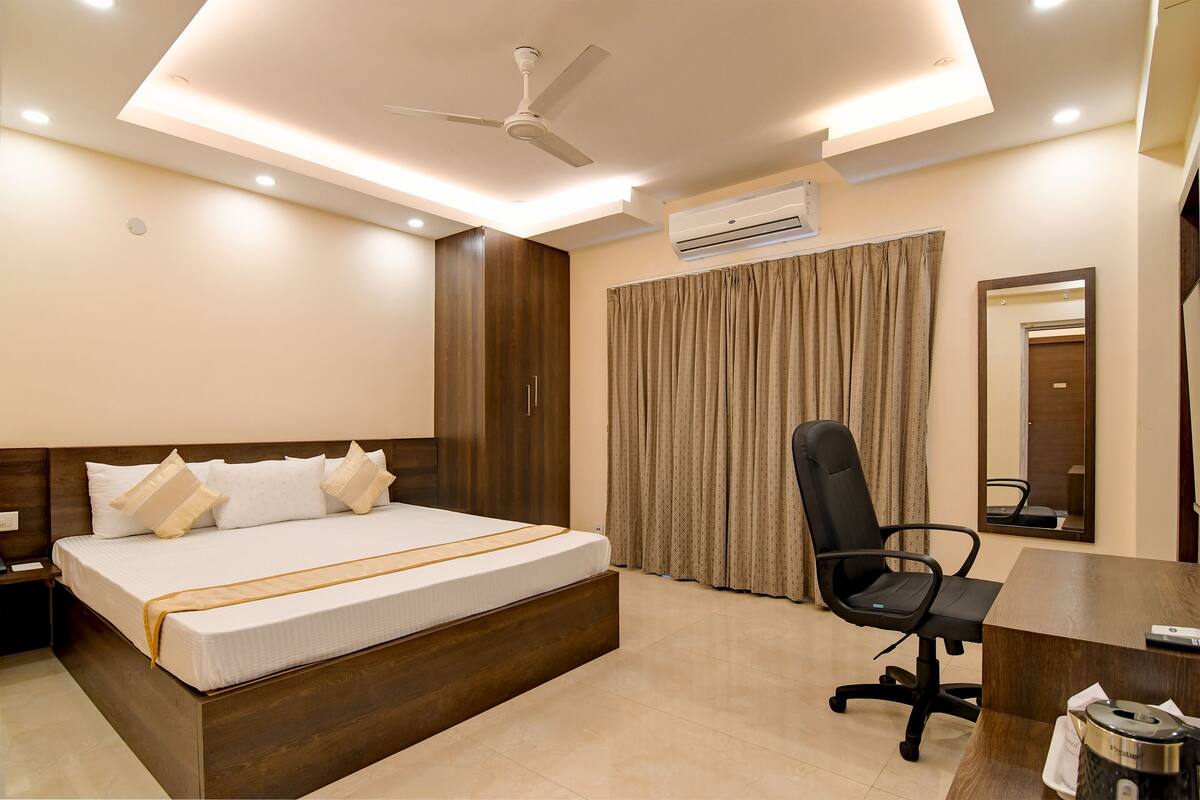 Una habitación de hotel con una cama, un escritorio, una silla, un ventilador de techo y aire acondicionado.