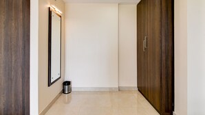 A hallway with a wooden door, a mirror, a trash bin, and a wardrobe. - AVS PRIME (Barasat)
