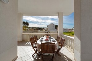 A covered outdoor dining area with a round table set for four, surrounded by wooden chairs. - 3727 Villa Stella Graziana by Barbarhouse (Porto Cesareo)
