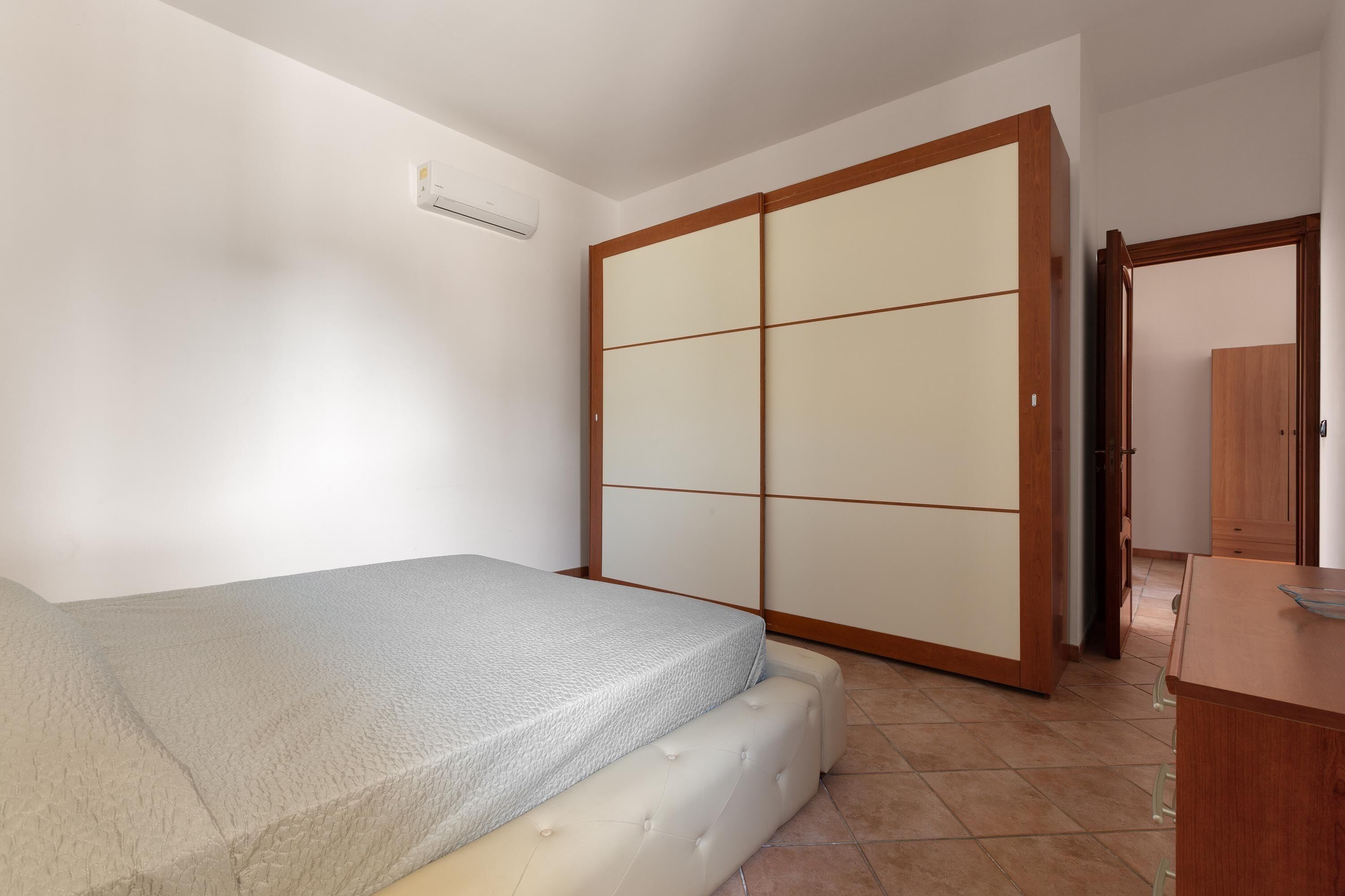 A bedroom with a bed, a wardrobe, and a small wooden dresser.